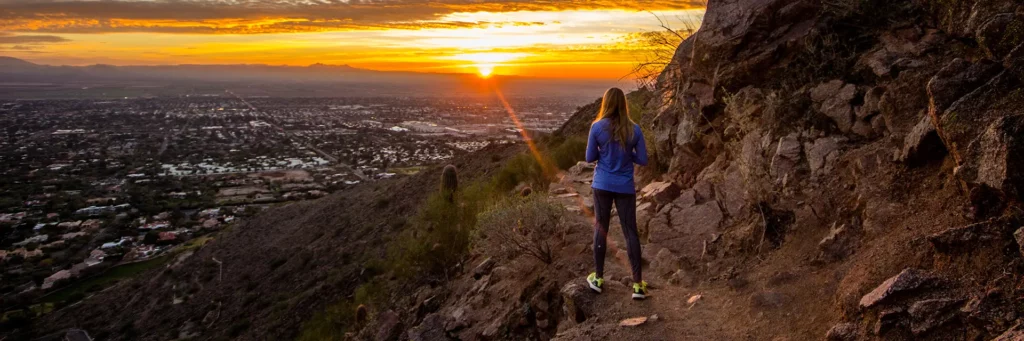 Phoenix Arizona Real Estate Market Update Banner - A Woman is Hiking On South Mountain Near Ahwatukee AZ