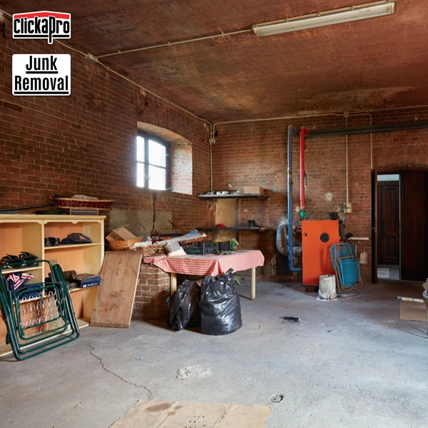 A trash bag an old chair and other old debris in a brick basement. This pile is ready for Clickapro's Basement Junk Removal Service